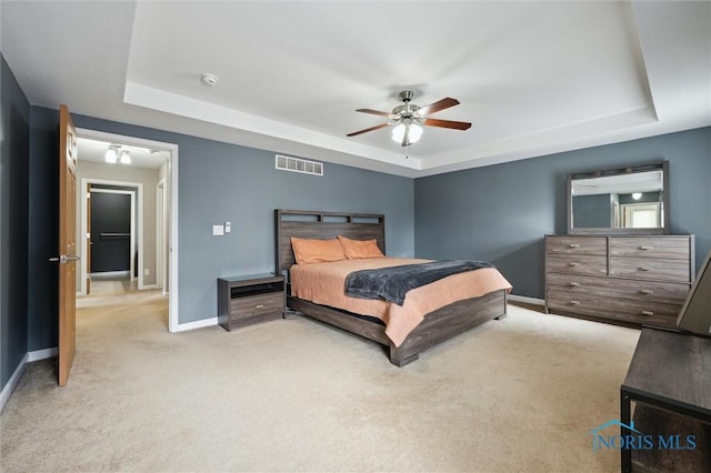 bedroom featuring a tray ceiling, carpet flooring, visible vents, and baseboards