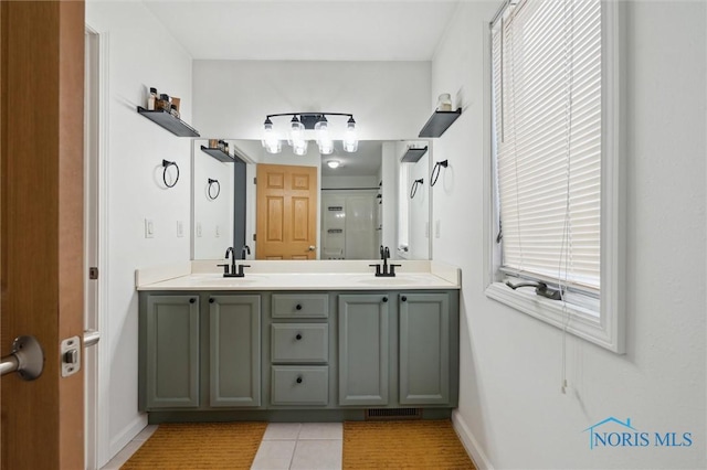 bathroom featuring double vanity, a shower with shower door, a sink, and tile patterned floors