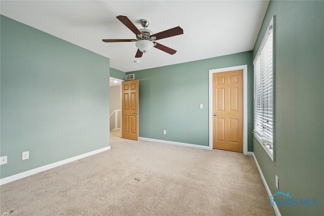 unfurnished bedroom with a ceiling fan, visible vents, light carpet, and baseboards