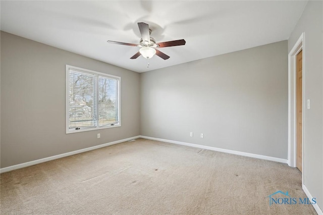 spare room featuring light carpet, baseboards, and a ceiling fan