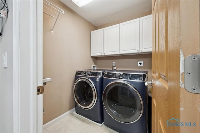 washroom with cabinet space, baseboards, and washer and clothes dryer