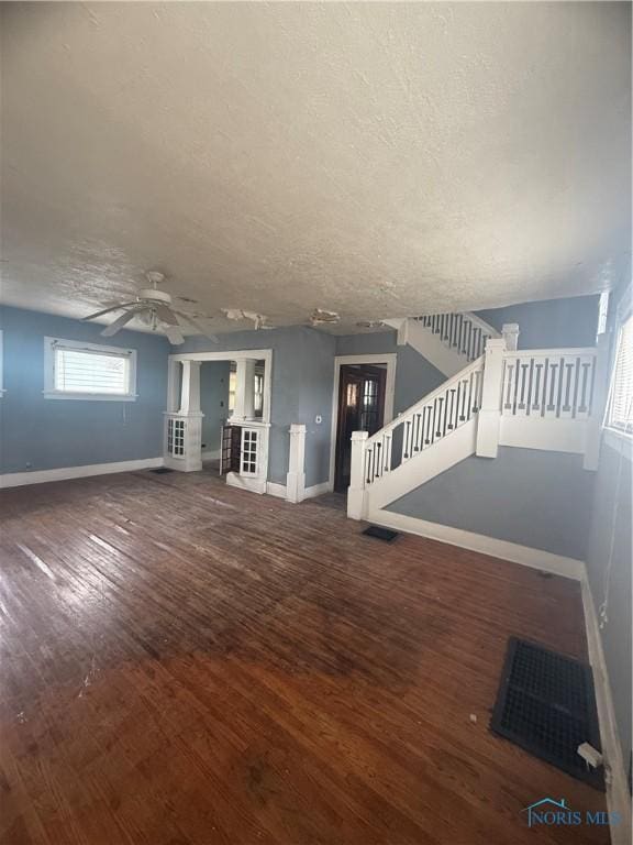 unfurnished living room featuring stairs, wood finished floors, and baseboards