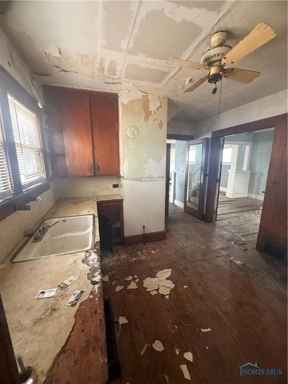 kitchen with light countertops, dark wood-type flooring, brown cabinetry, a sink, and ceiling fan