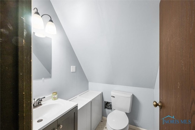 bathroom with toilet, vaulted ceiling, and vanity