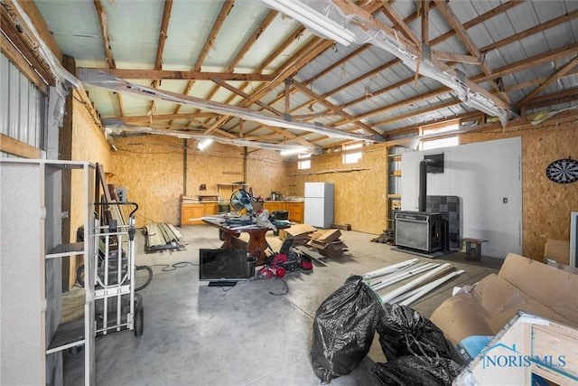 interior space with a garage, freestanding refrigerator, a wood stove, and metal wall