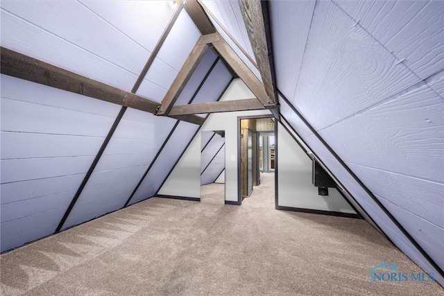 additional living space featuring lofted ceiling with beams and carpet