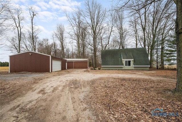 exterior space featuring a garage, driveway, and an outdoor structure