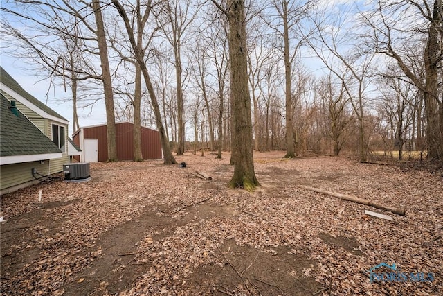 view of yard featuring dirt driveway, central air condition unit, a garage, a pole building, and an outdoor structure