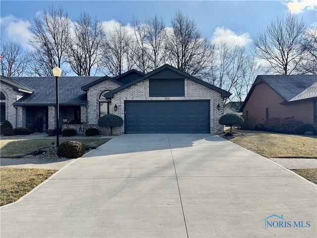 view of front of property featuring a garage, a front yard, brick siding, and driveway