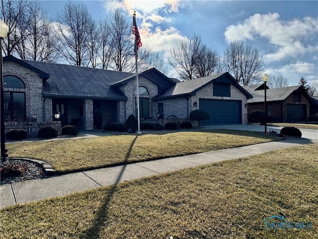 view of front facade with driveway, an attached garage, a front lawn, and brick siding