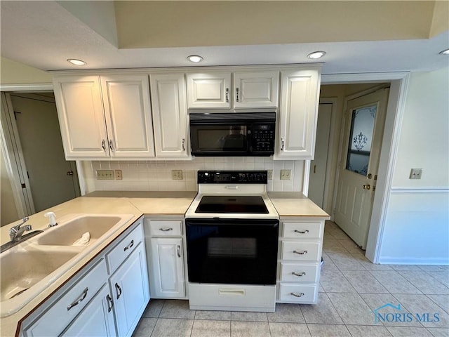 kitchen featuring black microwave, a sink, white cabinetry, light countertops, and electric range oven