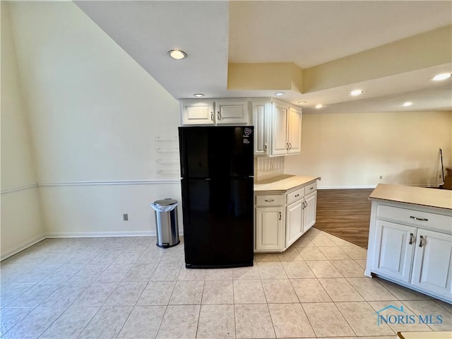 kitchen with light countertops, decorative backsplash, freestanding refrigerator, light tile patterned flooring, and baseboards