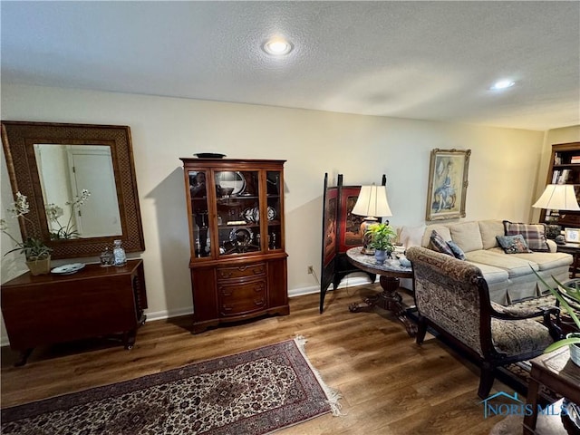 living area with recessed lighting, a textured ceiling, baseboards, and wood finished floors