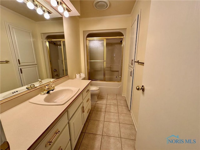 full bath with bath / shower combo with glass door, toilet, tile patterned floors, crown molding, and vanity