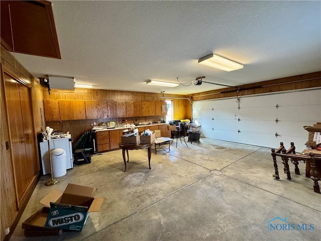 garage with wooden walls, washer / clothes dryer, and a garage door opener