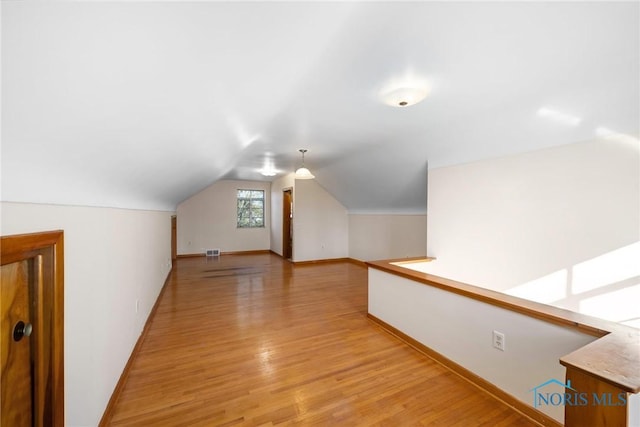 8134 W Central Ave, Toledo, OH 43617 - additional living space with visible vents, baseboards, light wood-style floors, and vaulted ceiling