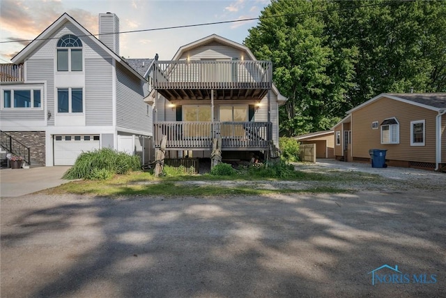 view of front of home featuring driveway, a chimney, and an attached garage