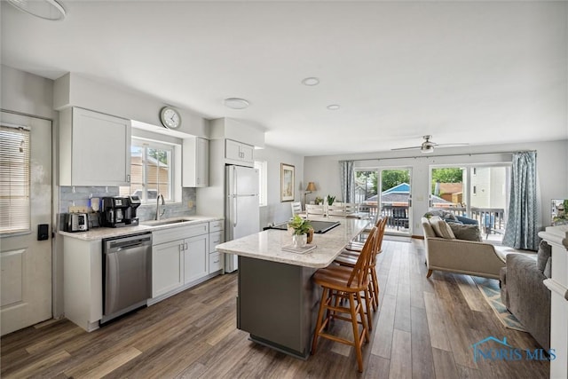 kitchen featuring a breakfast bar area, open floor plan, white cabinets, a sink, and dishwasher