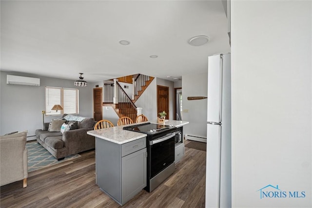 kitchen featuring a baseboard radiator, electric stove, a wall mounted AC, gray cabinets, and freestanding refrigerator