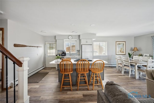 dining area featuring stairway, baseboard heating, and wood finished floors