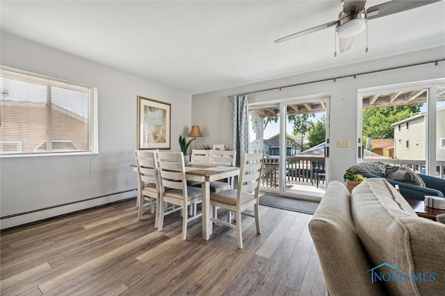 dining area with a baseboard radiator, ceiling fan, and wood finished floors