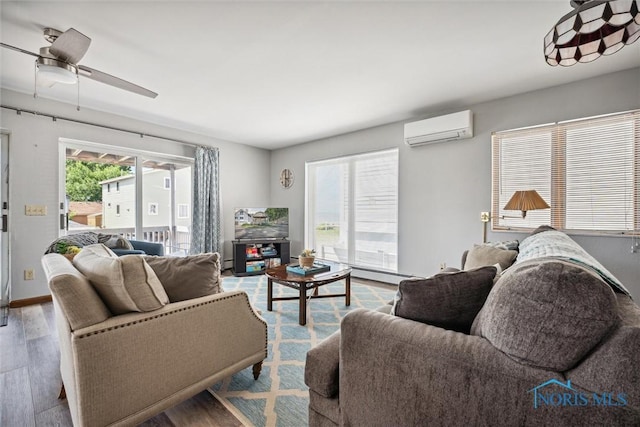 living area with wood finished floors, ceiling fan, baseboards, and a wall mounted AC