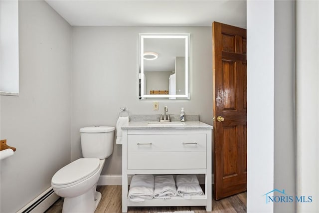 bathroom with toilet, baseboard heating, vanity, wood finished floors, and baseboards