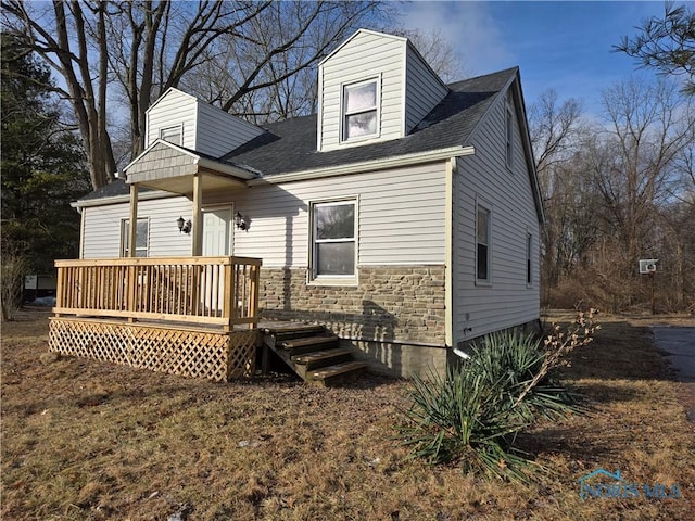 rear view of property with stone siding and a wooden deck