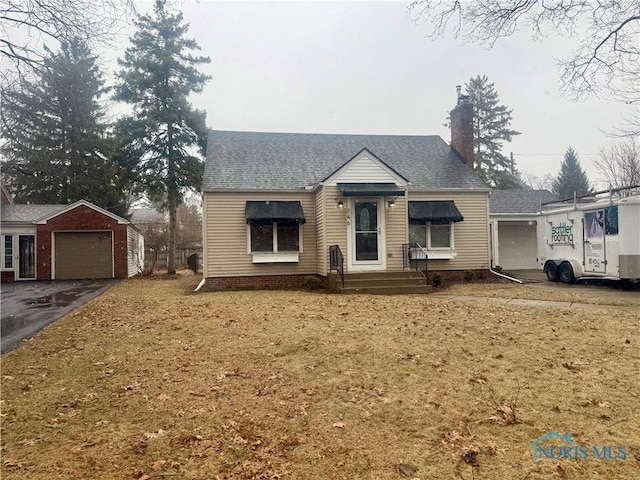 bungalow featuring driveway, a chimney, a detached garage, and roof with shingles