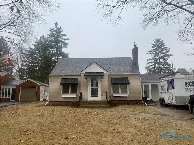 view of front of home with an outbuilding, a garage, driveway, roof with shingles, and a chimney