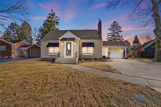 view of front of property featuring a yard, driveway, a chimney, and a shingled roof