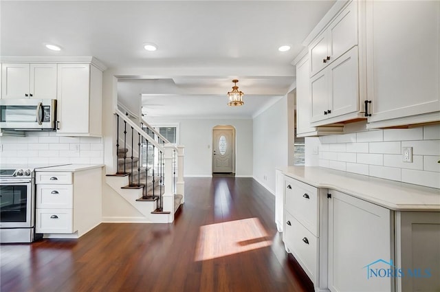 kitchen featuring decorative backsplash, baseboards, dark wood-style floors, light countertops, and appliances with stainless steel finishes