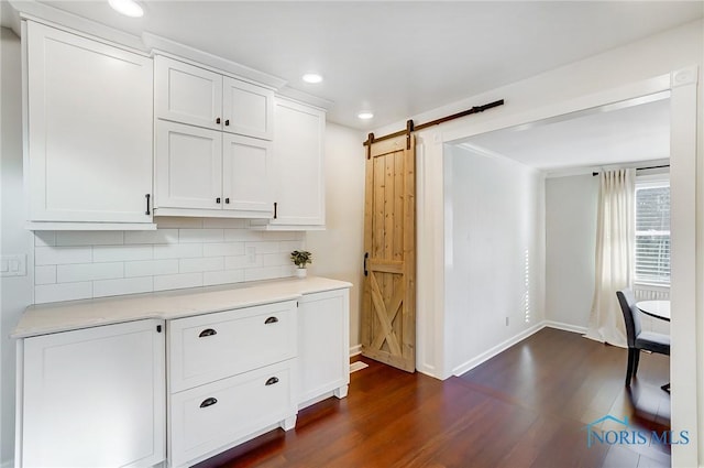 interior space with dark wood-style flooring, baseboards, recessed lighting, a barn door, and backsplash
