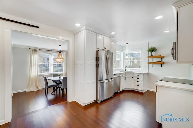 kitchen featuring a sink, pendant lighting, stainless steel appliances, and dark wood-type flooring