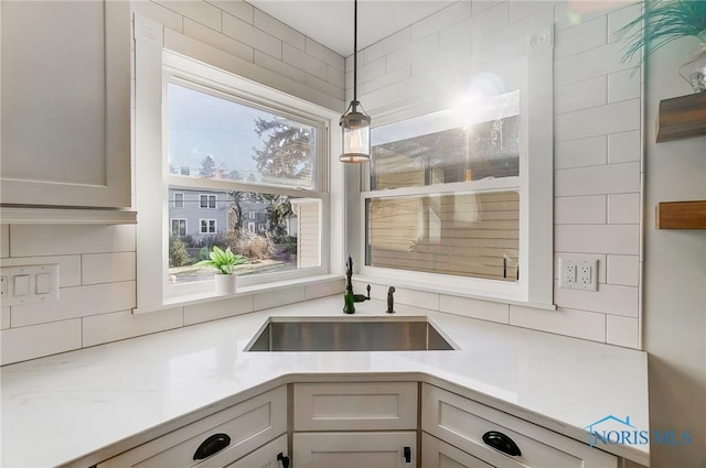room details with a sink, light countertops, decorative backsplash, and decorative light fixtures