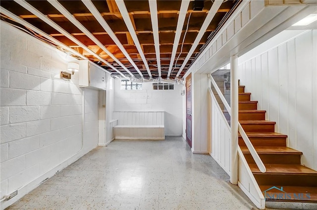 below grade area featuring stairs and concrete block wall
