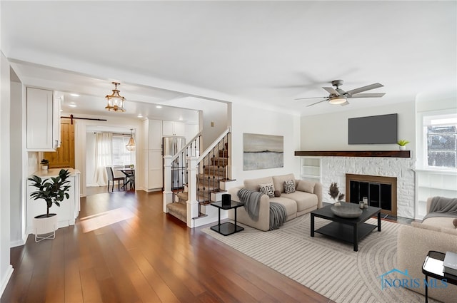 living area with dark wood-style flooring, a ceiling fan, and a healthy amount of sunlight
