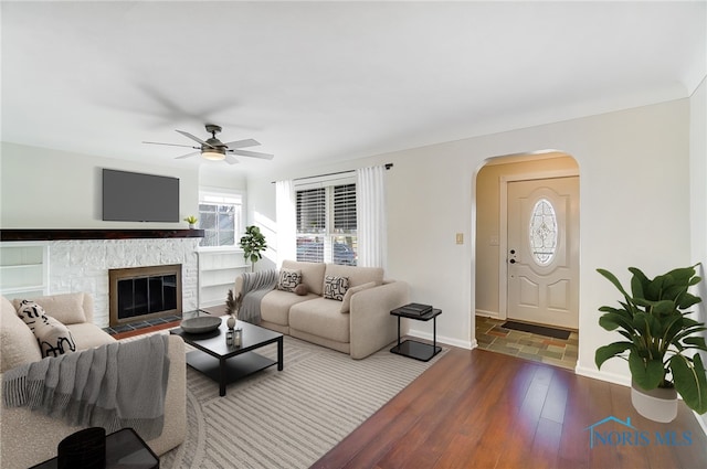 living room featuring arched walkways, ceiling fan, hardwood / wood-style flooring, and a wealth of natural light
