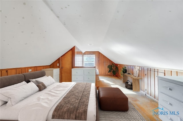 bedroom featuring wooden walls and vaulted ceiling