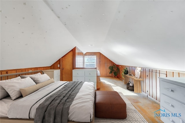 bedroom with wood walls, light wood finished floors, and lofted ceiling