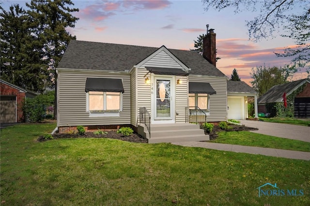 bungalow featuring a front yard, a chimney, a shingled roof, an attached garage, and driveway