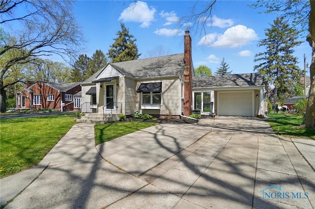 view of front facade with an attached garage, a chimney, a front yard, and concrete driveway