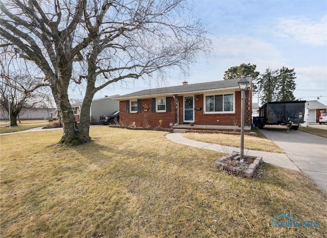 view of front of property featuring concrete driveway, brick siding, a front lawn, and a chimney