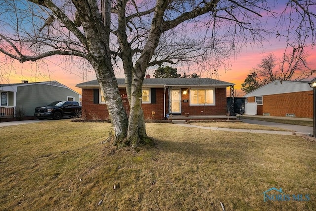 ranch-style home with brick siding, a yard, and a chimney