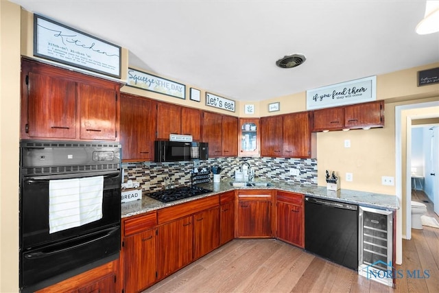 kitchen with wine cooler, a sink, light wood-style floors, a warming drawer, and black appliances