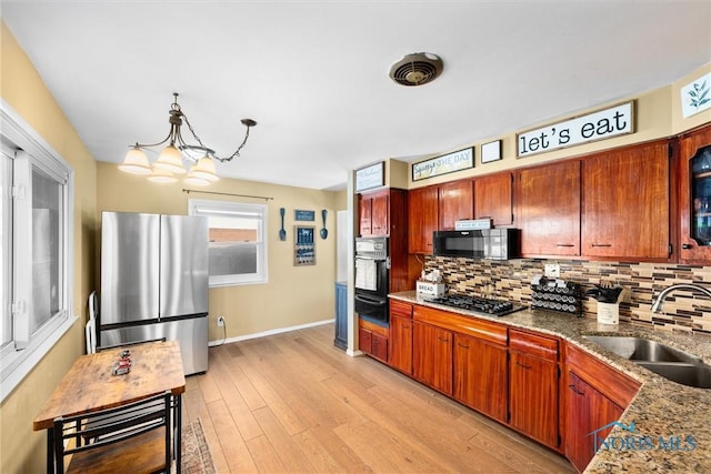 kitchen featuring stainless steel appliances, a sink, backsplash, a warming drawer, and light wood finished floors