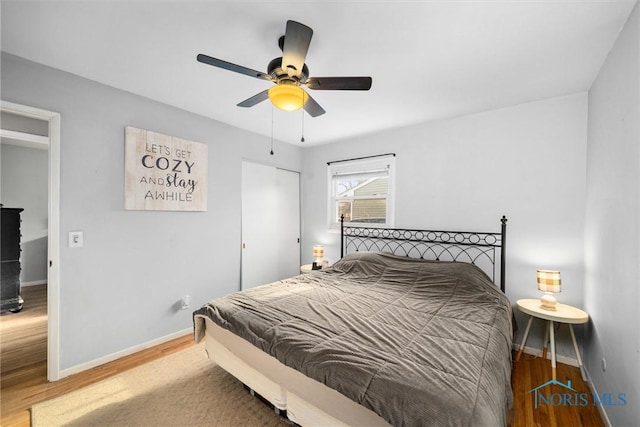 bedroom featuring a closet, ceiling fan, baseboards, and wood finished floors