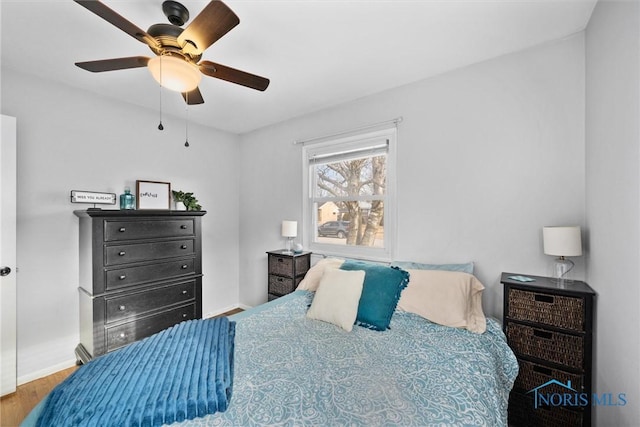 bedroom featuring a ceiling fan, baseboards, and wood finished floors