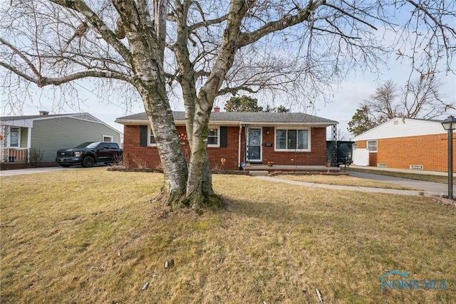 single story home featuring a chimney, a front lawn, and brick siding