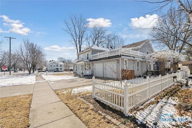 view of side of home with a fenced front yard, driveway, a balcony, and an attached garage